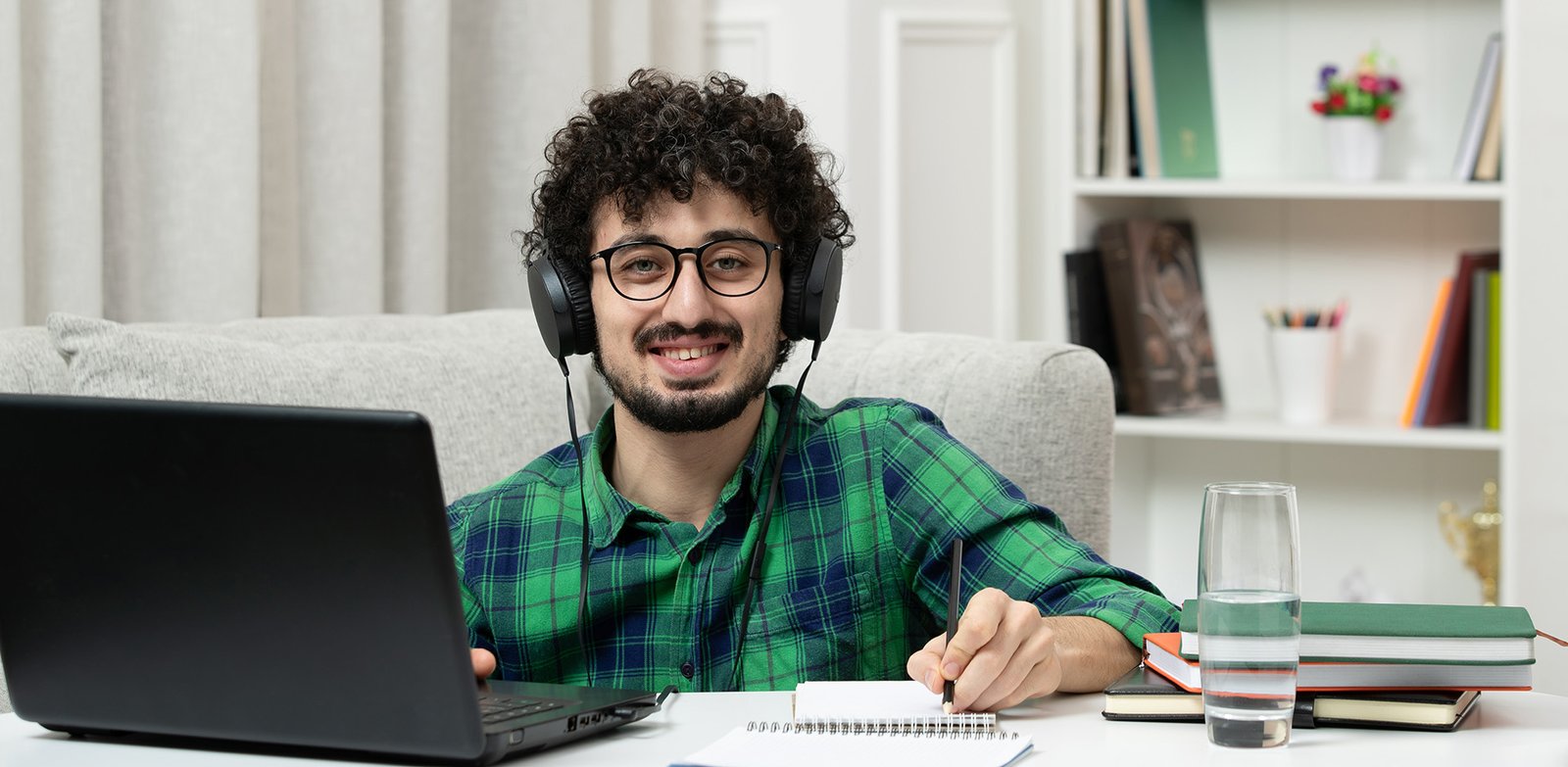 student online cute young guy studying on computer in glasses in green shirt smiling